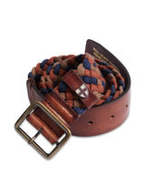 The Pratese Belt - Brown by Blue de Gênes is handmade in Italy with vegetable-tanned leather. It features a brown leather strap with a brass buckle and is intertwined with multicolored woven fabric displaying blue, brown, and red patterns, highlighting its textured elegance and contrasting colors.