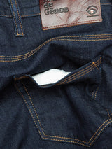 Close-up of Blue de Gênes Repi Dai V Dark Jeans in dark blue denim, featuring a waistband leather patch with text and comfort stretch fabric. The visible pocket is highlighted by orange stitching.