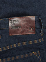 Close-up of Repi Dai V Dark Jeans by Blue de Gênes, featuring yellow stitching and a brown leather patch on the waistband. Made from comfort stretch denim, the patch reads Blue de Gênes with a small eye logo and cross detail for added charm.