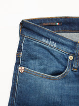 Close-up of Blue de Gênes Repi Dragon Dark Used Jeans in comfort stretch denim, featuring visible stitching, a small emblem near the front pocket, and an Italian flag tag stating Made in Italy. These regular slim-fit jeans have classic brass button accents.