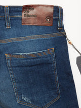 Close-up view of Blue de Gênes Repi Dragon Dark Used Jeans in denim blue, featuring a brown leather patch with embossed text above the back pocket, orange stitching accents, and a tag attached with a string. Made from comfort stretch denim for regular slim fit, combining style with flexibility.