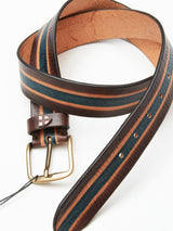 The Tino Belt - Brown Stripe by Blue de Gênes is coiled with dark brown, tan, and blue stripes. Handmade in Italy from vegetable-tanned full grain leather, it features a brass buckle and multiple adjustment holes, blending elegance with functionality.