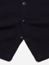 Close-up of the Zorba Knit Waistcoat by Blue de GĂȘnes, featuring four corozo nut buttons on textured navy merino wool. The waistcoats pointed hem forms a V-shape against a white background.