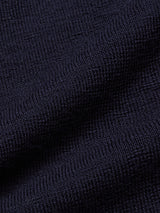 Close-up of the Zorba Knit Waistcoat - Navy by Blue de GĂȘnes. The dark blue merino wool fabric features a grid-like weave with gentle folds, creating shadows and highlights reminiscent of a finely knit waistcoat.