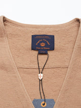 Close-up of a taupe knit waistcoat with Corozo Nut buttons, featuring a navy Blue de Gênes label at the neckline reading Ericco Loro Piana Large. Made from soft Merino wool, it has a tag with a small cross charm attached below.