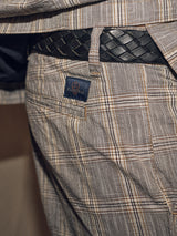 Close-up of a person wearing plaid-patterned pants with a visible pocket, styled with the Intero Belt in black by Blue de Gênes. A small logo tag is sewn on the pants near the pocket, adding a vintage touch.