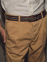 A person in a white shirt tucked into tan chinos with a Blue de Gênes Tino Belt - Brown Stripe. Their right hand is in their pocket.