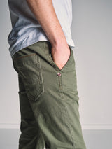 A person models the Blue de Gênes Paulo Pavia 1 V2 Chino - Army, styled with a white t-shirt and one hand in their pocket, shown from the waist down against a plain background.