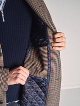 A person opens the Blue de Gênes Massone Check Coat - Multi Check to reveal its quilted lining and inner pocket in matching check fabric—perfect for a refined winter look.