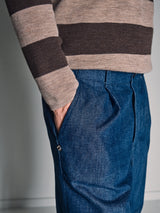 A person stands with one hand in their pocket, showing only the torso and upper legs, wearing the Blue de Gênes Toyama Stripe Knit L/S - Oat sweater and blue jeans.