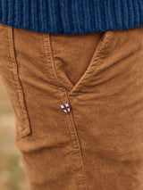 Close-up of a person wearing Blue de Gênes Paulo Tucan Chino in Biscotto, featuring a shield emblem on the pocket, paired with a dark blue knit sweater.