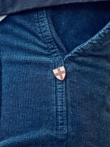 Close-up of a person wearing Blue de Gênes Paulo Tucan Chino in navy, expertly crafted for comfort stretch and made in Italy. A small shield-shaped pin with a white cross on a red background is attached near the pocket seam.