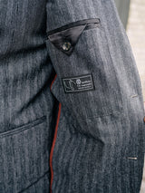 Close-up of the Leopardi Dori Blazer by Blue de Gênes reveals its label, impeccably crafted in an Italian cotton-wool blend with a brown plaid pattern. It features a red lining and a small inner pocket with black trim.