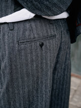 Close-up of a person wearing the Panco Dori Chino - Grey stripe by Blue de Gênes, featuring a back pocket with a buttoned flap. The Italian cotton-wool blend fabric shows an irregular pinstripe pattern, with a white shirt peeking from beneath the suit jacket.