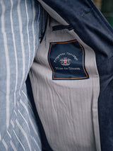 Close-up of the Amos Blazer - Dark Navy by Blue de Gênes, showing its inner cotton canvas lining with a stitched “Progetto Heritage Blue de Gênes” label, crest, and contrasting striped fabric panels.