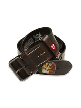The Gari Belt by Blue de Gênes is dark brown leather with visible stitching and a metal buckle, featuring a small red and white shield emblem like Austrian army belts, plus a worn patch illustration.