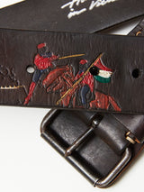 Close-up of the Gari Belt - Brown by Blue de Gênes, featuring premium leather with embossed soldiers on horseback, one with a spear and the other a flag resembling Indias. The belt is completed with a metal buckle.