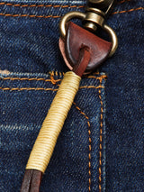 Close-up of the Blue de Gênes BGsavino Key Hanger - Brown, crafted from cow leather with brass hardware and beige thread wrap, attached to a blue denim belt loop and finished with a logo rivet.
