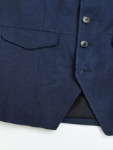Close-up of the Casella Officers Blazer - Dark Navy by Blue de Gênes, featuring three black buttons, two flap pockets, and visible brushed cotton fabric. The jacket is partially open at the bottom, revealing a black lining reminiscent of vintage parade uniforms.