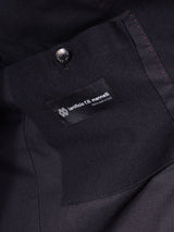 Close-up of the Black Casella Officers Blazer by Blue de Gênes, showing a label from Ilanificio F.lli Maranelli and Made in Italy. The blazer, crafted with brushed cotton fabric, features a black button above the label and red stitching reminiscent of vintage parade uniforms.