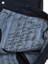 The image shows the inside of Blue de Gênes Teo Chino - Navy, featuring handwritten text in black ink on pinstriped lining with cursive writing across garment-dyed fabric for a distinct finish.