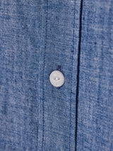 Close-up of the Miguel Chambray Shirt in Lt. Denim Blue by Blue de Gênes, highlighting the soft cotton fabric, visible stitching, and a white Corozo nut button sewn with blue thread for a touch of craftsmanship and elegance.