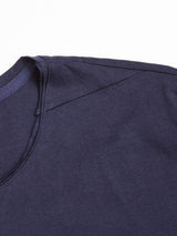 Close-up of the upper part of a dark navy Sagi Nuovo T-shirt by Blue de Gênes against a white background. The premium cotton texture and shoulder stitching are visible, showcasing the garments design and quality, making it a wardrobe staple.