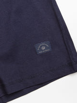 A close-up shows a dark navy fabric with a small rectangular label stitched near the edge. Featuring light text, it suggests its a Sagi Nuovo T-shirt by Blue de Gênes. Crafted from premium cotton, this piece is designed for comfort and style, making it a wardrobe staple.