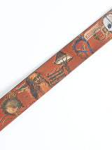 The Da Vinci Belt 4 cm by Blue de Gênes features brown leather with Leonardo Da Vinci-inspired abstract designs, including pyramids, lines, and circular patterns in earthy tones. This premium accessory is showcased diagonally on a white background.