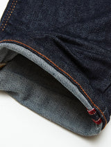 Close-up of Repi Dai V Dark Jeans by Blue de Gênes, featuring dark blue denim with orange stitching and a lighter striped inner pattern. Red-detailed selvedge edge highlights comfort stretch material, blending style and comfort.