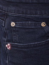 Close-up of a dark blue denim pocket with two copper rivets and a small red and white stitched emblem on the right. Expertly crafted in Italy, the Comfort Stretch Denim highlights Vinci 3325 Black Jeans texture, showcasing Blue de Gênes commitment to quality.