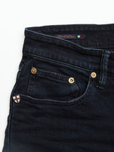 Close-up of Vinci 3325 Black Jeans by Blue de Gênes in blue black denim, showcasing front pockets with metal rivets and a coin pocket. Expertly crafted in Italy, they feature a cross emblem patch and a Made in Italy tag with the Italian flag at the waistband.