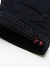 Close-up of the cuff of a Vinci 3325 Black Jeans pant leg by Blue de Gênes, showing intricate stitching. A small folded tag with red and black stripes is at the edge. Expertly crafted in Italy, the comfort stretch blue-black denim fabric appears textured, with neatly stitched seams.