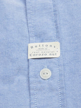 A close-up of the Sandro Oxford Shirt in blue from Blue de Gênes shows a button and label reading, Buttons made of real natural Corozo nut, highlighting its organic cotton construction.