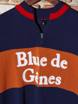 A navy and rust half-zip pullover made from Merino wool, displaying Blue de Gênes in white on the chest and featuring a red and navy-striped collar, reminiscent of the Tributo Cycling Jersey.