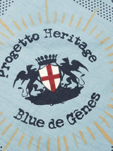 The light blue cotton fabric of the Bandana - Celeste from Blue de Gênes features a bold crest of winged lions, a red cross on a white shield, and Progetto Heritage Blue de Gênes text. Radiating lines and spotted patterns encircle the design, making it perfect for stylish scarves.