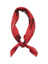 The Bandana - Red by Blue de Gênes features black and white abstract designs and numbers on soft cotton, tied in a loose knot. It includes a subtly faded logo print set against a plain white background.