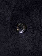 Close-up of a black Buffalo horn button on the Canna Carbonio Gillet by Blue de Gênes, made from Italian brushed cotton, with Bille de sens in gold lettering.