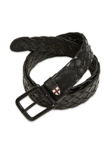 The Intero Belt - Black by Blue de Gênes is a coiled, black braided leather belt featuring a rectangular black buckle and hand-sewn stitches. A small shield emblem with a red cross near the buckle adds vintage charm.