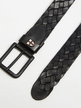 The Intero Belt - Black by Blue de Gênes features braided leather with a matte black metal buckle, showcasing intricate hand-sewn stitches and a subtle logo near the loop. Enhanced with a vintage treatment, its set against a plain, light background.
