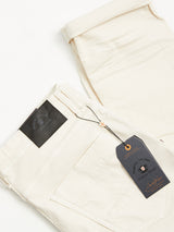 The Paulo Pavia 1 Chino - Ecru from Blue de Gênes is crafted from cotton stretch fabric and features a black patch with branded tag. Partially rolled cuffs offer both style and comfort, making them suitable for any occasion.