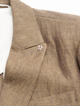 Close-up of the BGcricket Lin Blazer in Grey Mel by Blue de Gênes, featuring a lapel pin with a cross design. The linen and hemp blend blazer showcases its collar and part of the front pocket, paired with relaxed tailoring and a crisp white shirt underneath.