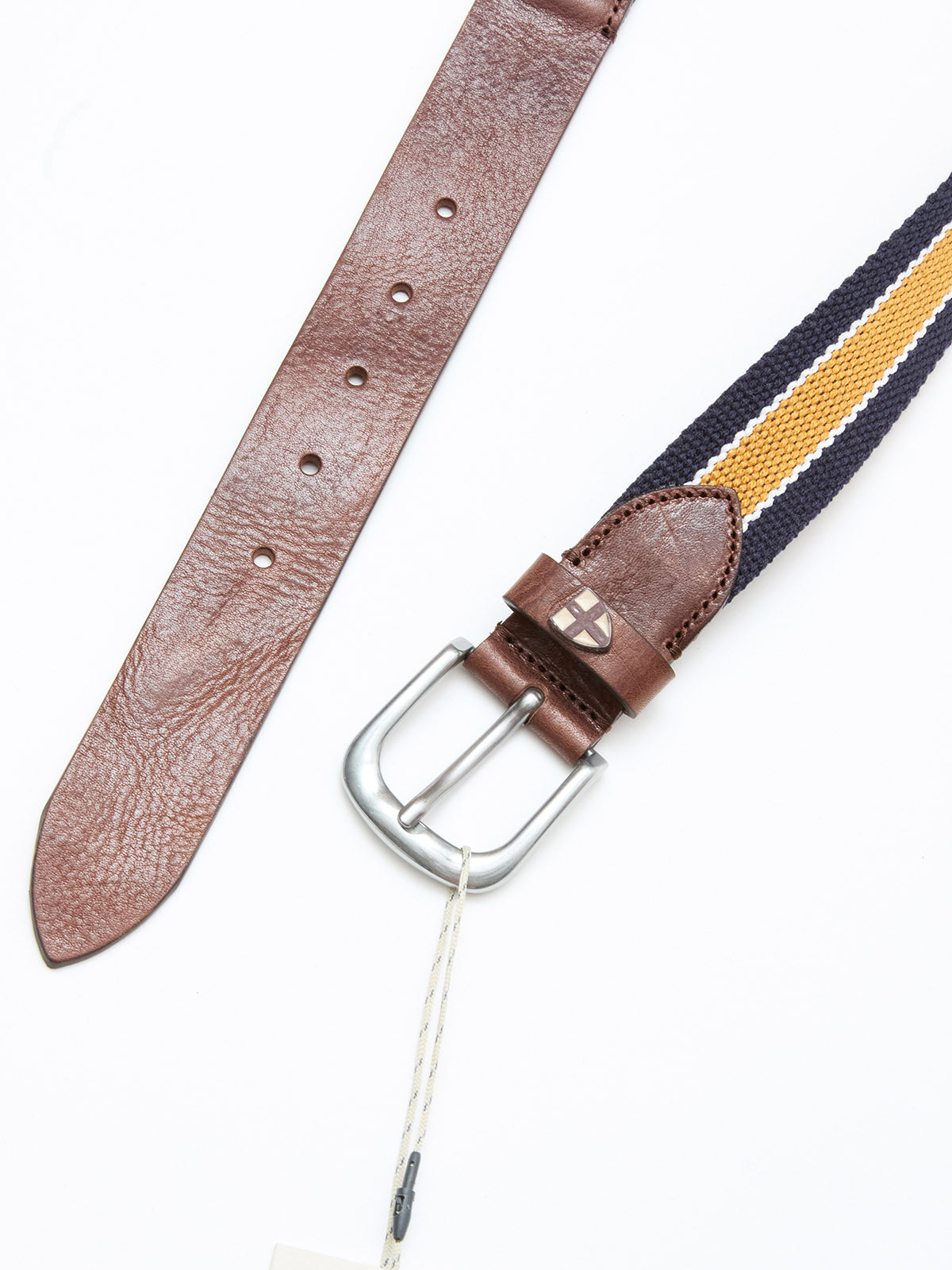 The Blue de Gênes BGcollege Belt - Navy Stripe features a brown leather buckle attachment and a navy blue and yellow striped strap, shown on a white background with a white tag hanging from the silver buckle.