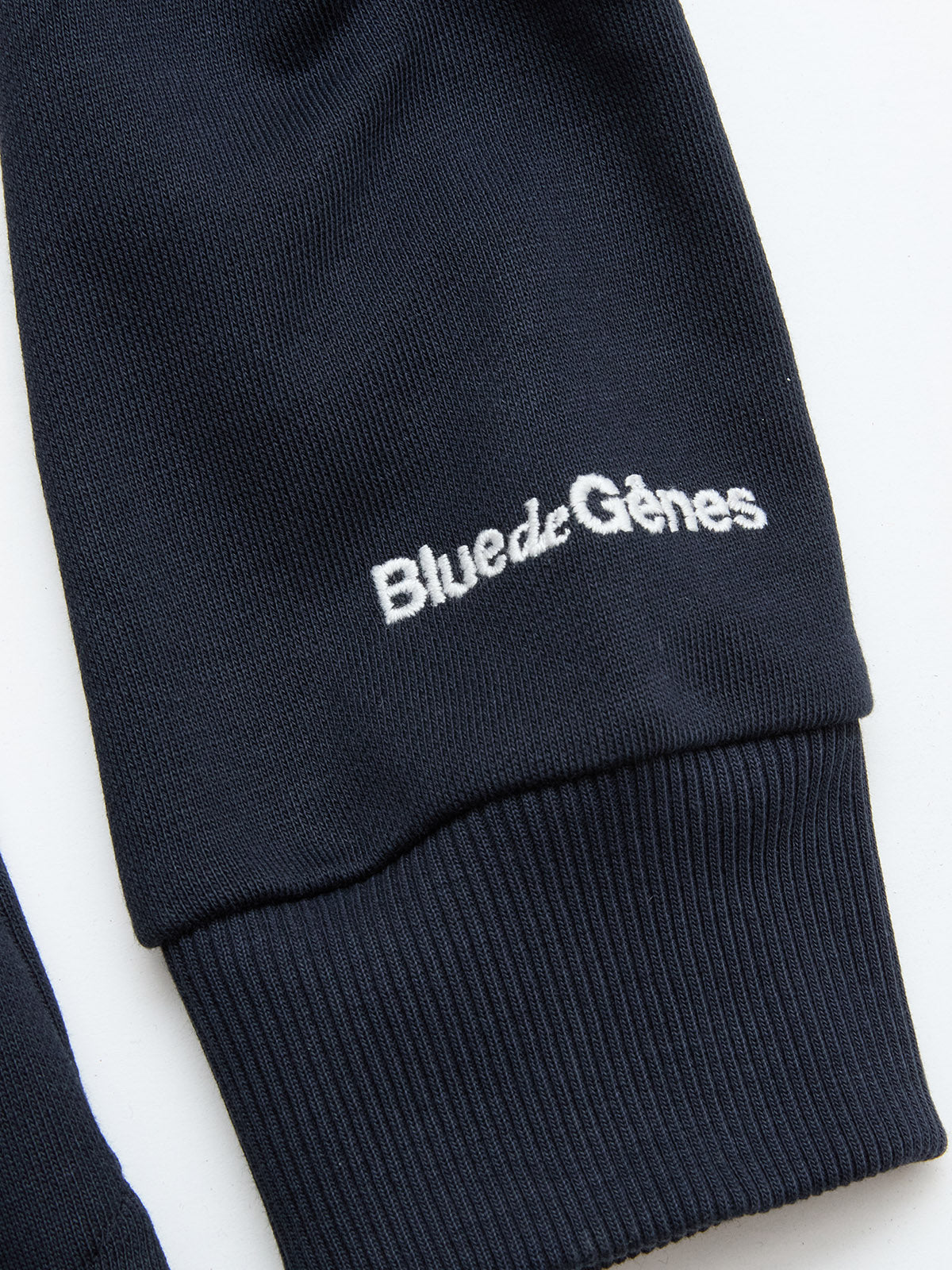 Close-up of the BGclubhouse Rugby Sweatshirt in navy by Blue de Gênes, crafted from soft cotton jersey with a ribbed cuff and featuring white embroidered “Blue de Gênes” text—highlighting its athletic heritage.