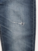 A close-up of the Blue de Gênes BGvinci Striker Jeans - Dark Distress, crafted in Italy from comfort stretch denim in a regular fit, featuring a small tear and frayed edges on the thigh area.