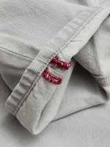 A close-up of BGgiacomo Color Jeans - Dolphin Grey by Blue de Gênes, crafted from rigid denim, with the cuffed leg showing two red embroidered stitches along the inner seam.