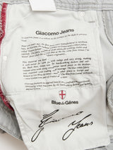 Close-up of the inside pocket of BGgiacomo Color Jeans - Dolphin Grey by Blue de Gênes, featuring brand heritage text, a red seam, Blue de Gênes logo, and signature on light gray rigid denim.