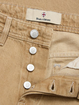 Close-up of tanin BGgiacomo Color Jeans by Blue de Gênes, crafted from rigid denim and featuring branded metal buttons with a signature label above the waistband. Detailed stitching and a partially open button fly accentuate these relaxed loose fit jeans.