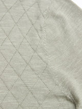 Close-up of the BGwally Diamond Polo in Shadow Green by Blue de Gênes, showcasing a subtle diamond-knit pattern on soft cotton-linen blend fabric with visible stitching along a curved seam.