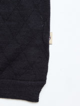 Close-up of the BGwally Diamond Polo in Dark Navy by Blue de Gênes, featuring a dark, quilted cotton-linen blend fabric with a subtle diamond-knit pattern. A small beige tag with a partial logo is visible on the side against a plain white background.
